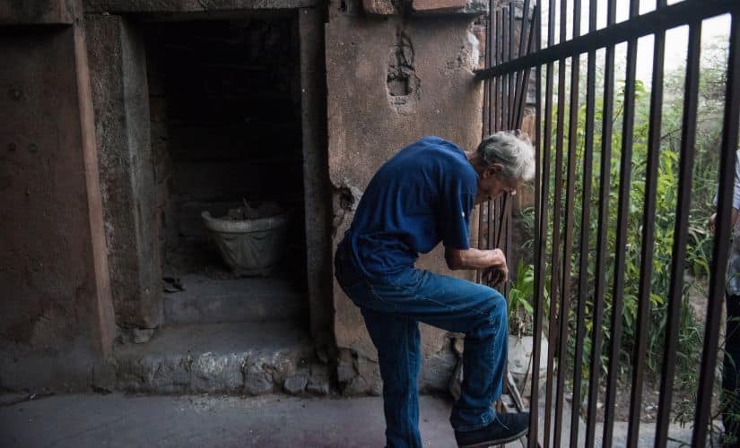 Prince Cyrus of Oudh opens a path to his family home in New Delhi, June 8, 2016. For 40 years, journalists chronicled the eccentric royal family of Oudh, deposed aristocrats who lived in a ruined palace in the Indian capital — a tragic, astonishing story, but was it true? (Andrea Bruce/The New York Times)