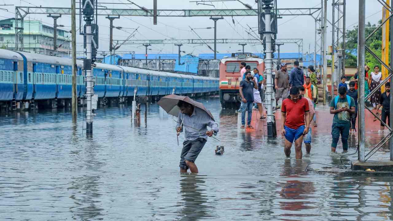 Passengers walk on waterlogged rail tracks at Ernakulam in Kochi in October 2019 after record, off-peak monsoon in the region. Image: Getty