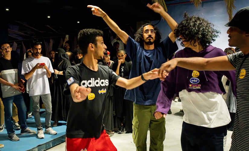 Mohammed Alhamdan (third from left) dancing with friends at a pop-up shop event in Riyadh on October 10. By Tasneem Alsultan © 20xx The New York Times