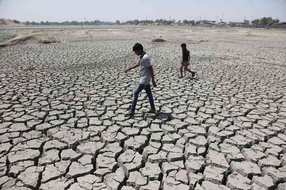 boys on their way to play cricket walk through a dried patch of Chandola Lake in Ahmadabad, India. Image credit: AP