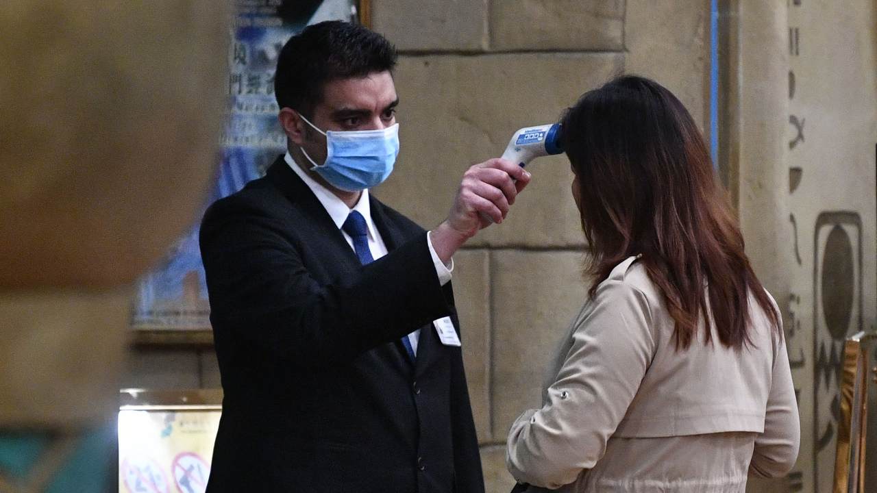 A staff member checks the temperature of a guest entering the casino of the New Orient Landmark hotel in Macau on January 22, 2020, after the former Portuguese colony reported its first case of the new SARS-like virus that originated from Wuhan in China. - Macau on January 22 reported its first confirmed case of the new SARS-like coronavirus as authorities announced all staff in the city's bustling casinos had been ordered to wear face masks. (Photo by Anthony WALLACE / AFP) / The erroneous mention[s] appearing in the metadata of this photo by Anthony WALLACE has been modified in AFP systems in the following manner: [entering the casino of the New Orient Landmark hotel] instead of [entering the New Orient Landmark hotel]. Please immediately remove the erroneous mention[s] from all your online services and delete it (them) from your servers. If you have been authorized by AFP to distribute it (them) to third parties, please ensure that the same actions are carried out by them. Failure to promptly comply with these instructions will entail liability on your part for any continued or post notification usage. Therefore we thank you very much for all your attention and prompt action. We are sorry for the inconvenience this notification may cause and remain at your disposal for any further information you may require. (Photo by ANTHONY WALLACE/AFP via Getty Images)