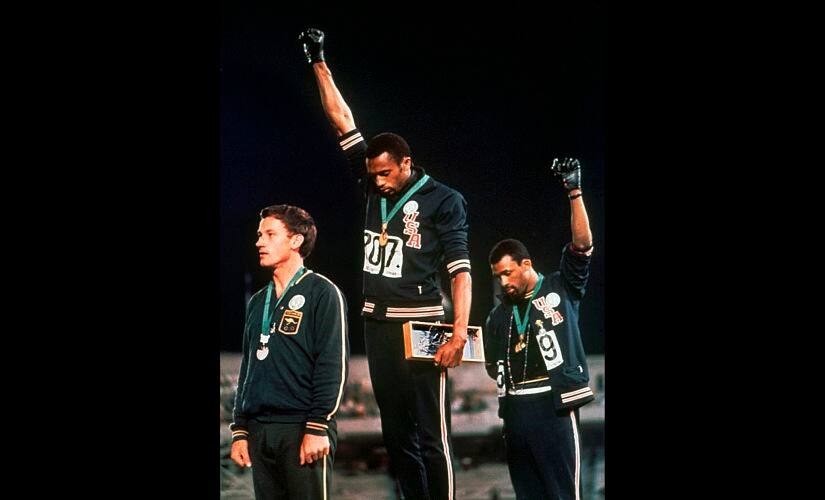 File photo from October 1968 showing US athletes Tommie Smith (centre), and John Carlos raising their gloved fists after Smith received the gold and Carlos the bronze for the 200m run at the Olympics AP Photo