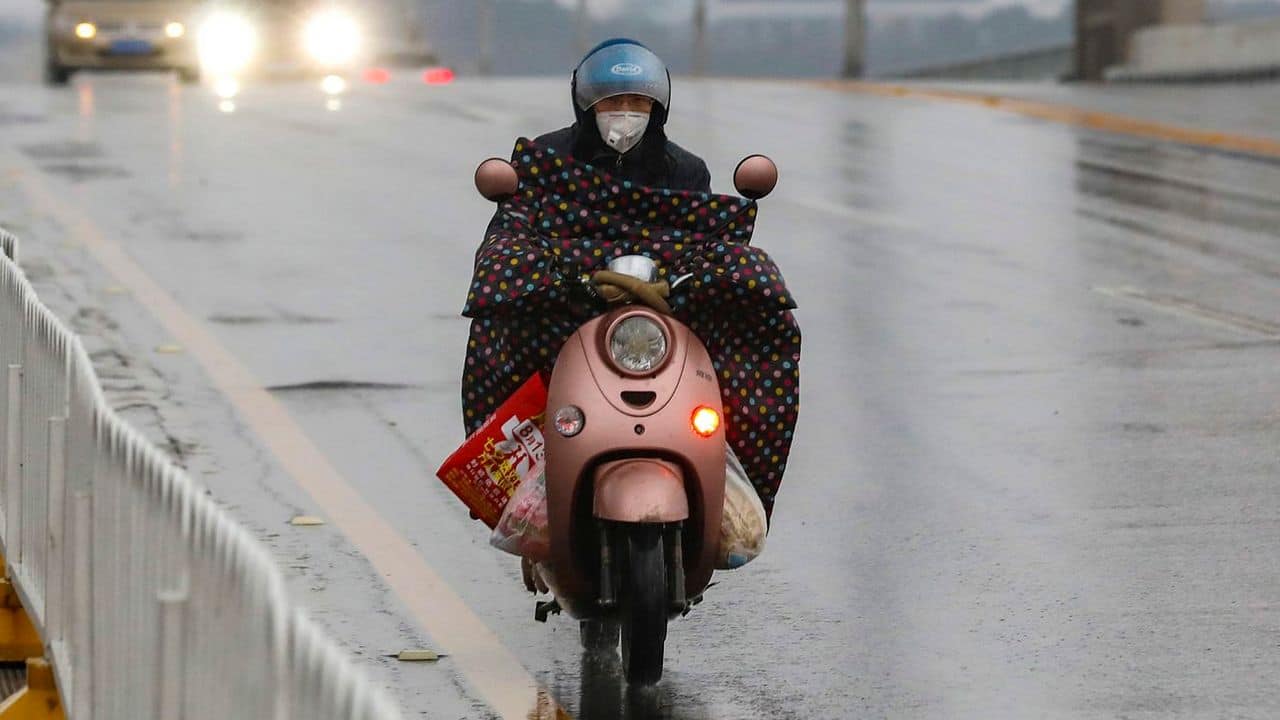 A motorcyclist wearing a face mask, rides across a bridge in Wuhan in central China’s Hubei province. Image credit: AP
