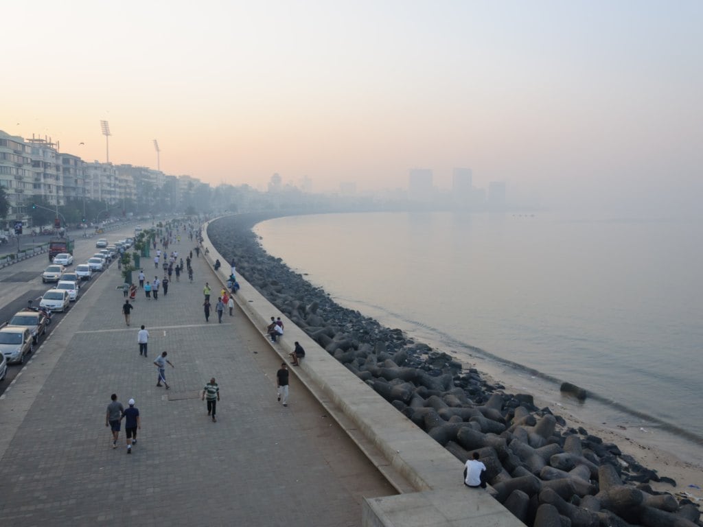 Residents of South Mumbai take an early morning stroll, exercise, jog along Marine Drive with skyscrapers and towers visible through a visible haze. Image: Getty