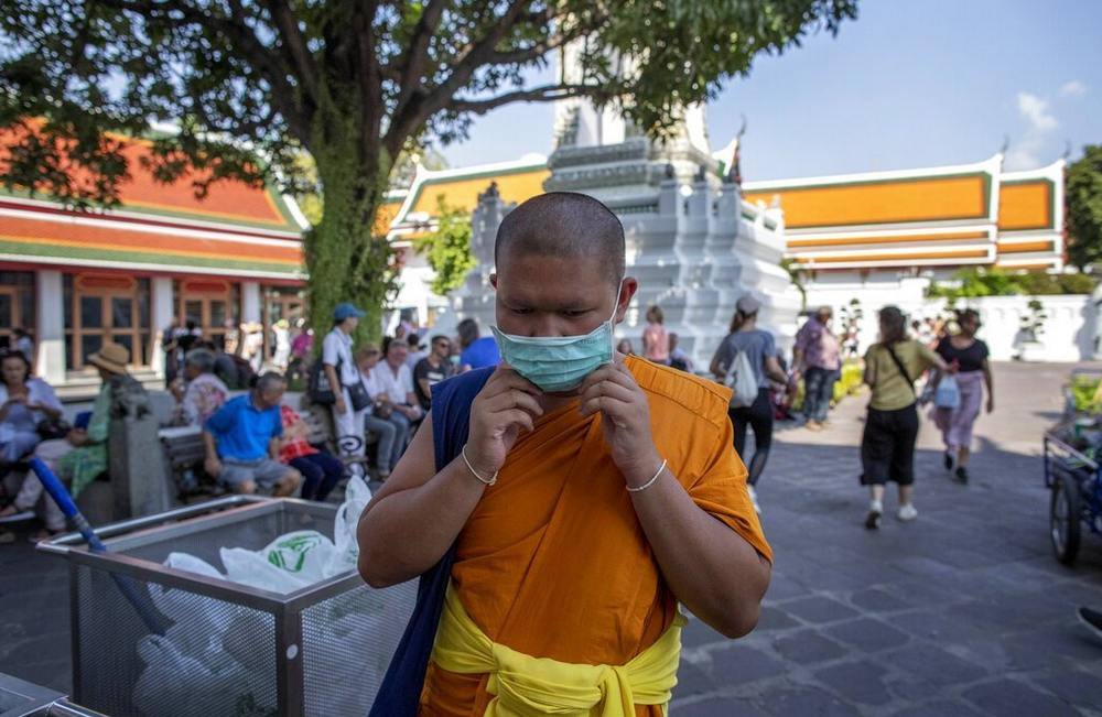 A Buddhist monk adjusts his face mask at the Wat Pho in Bangkok, Thailand. Image credit: AP