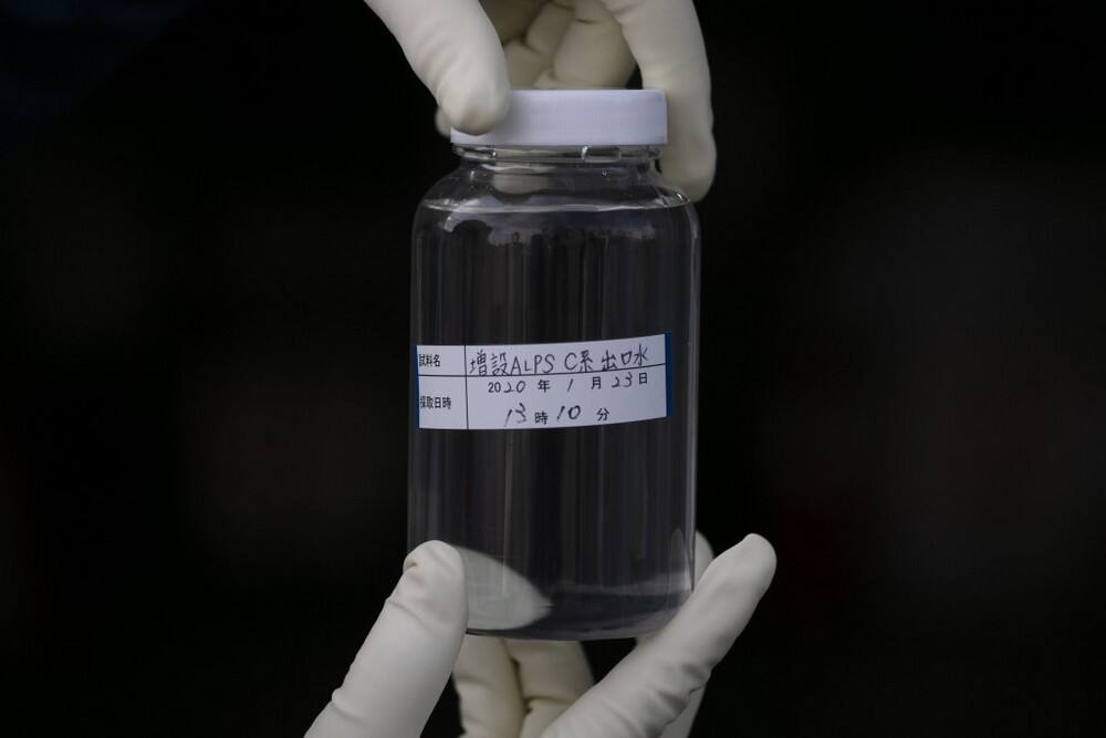 a worker shows a bottle containing treated water at the Fukushima Dai-ichi nuclear power plant in Okuma, Fukushima Prefecture, Japan Image credit: AP