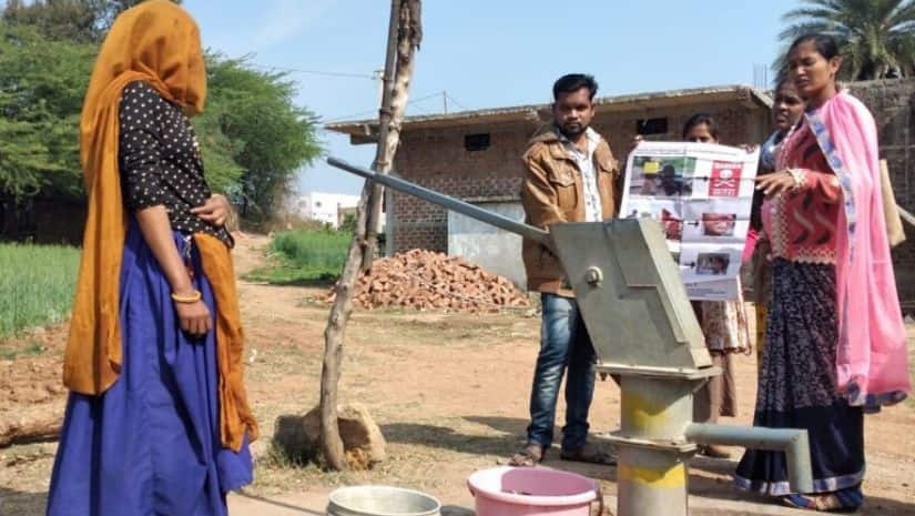 Pinky Alawa and Sapna Rawat (right) communicate the issue of impacts of high fluoride in water on health to women in Alirajpur, Madhya Pradesh. The yellow ring on the pump indicates water that has fluoride at concentrations much higher than the average value. Image via Mongabay-India/ Sahana Ghosh