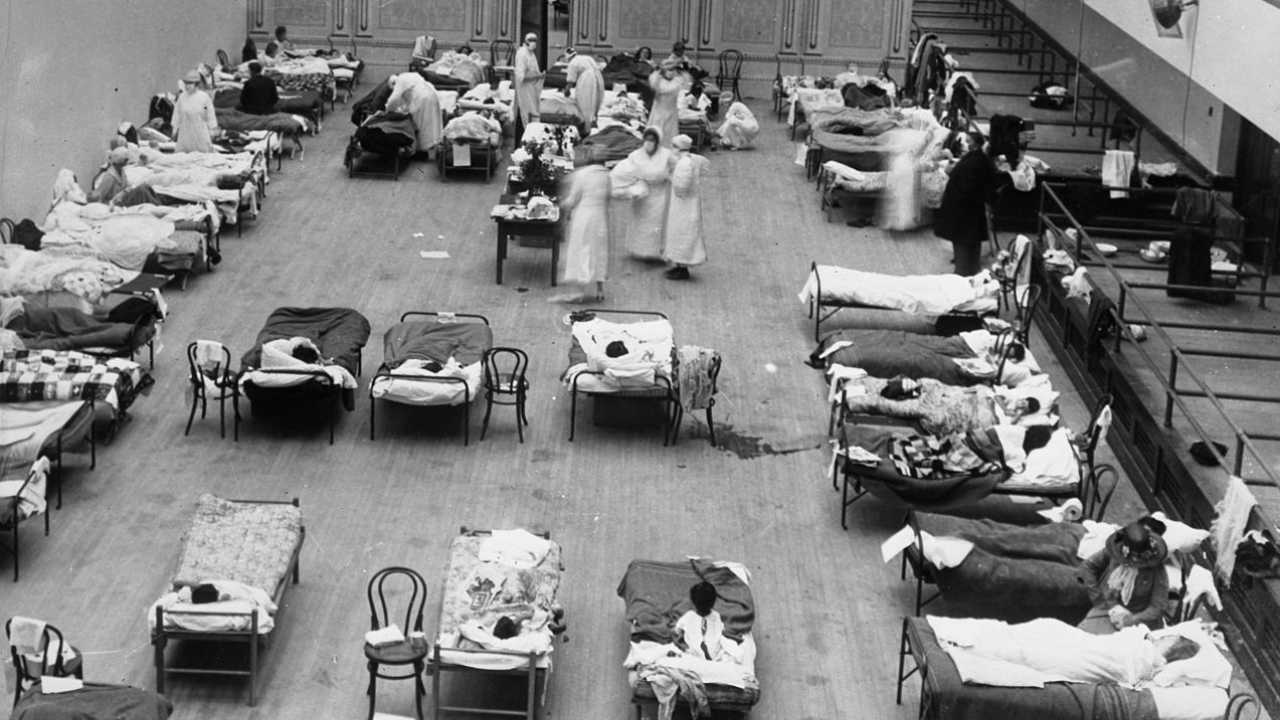 The photograph depicts volunteer nurses from the American Red Cross tending influenza sufferers in the Oakland Auditorium, Oakland, California, during the influenza pandemic of 1918. Image credit: Wikipedia 