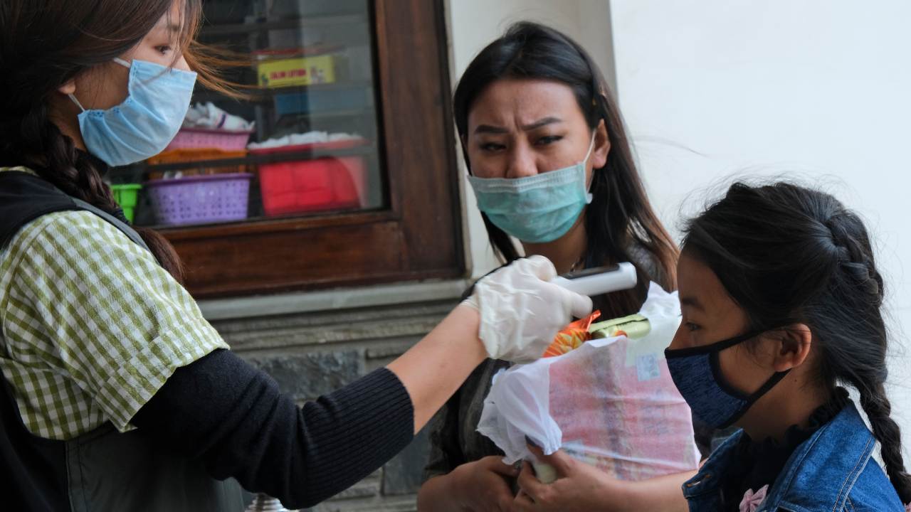 A medical staff checks the temperature of a little girl at the entrance of Oking Hospital in Kohima, capital of the northeastern Indian state of Nagaland, Monday, April 13, 2020. A man from Nagaland state has tested positive for COVID- 19, becoming the first case from the state. The new coronavirus causes mild or moderate symptoms for most people, but for some, especially older adults and people with existing health problems, it can cause more severe illness or death. (AP Photo/Yirmiyan Arthur)