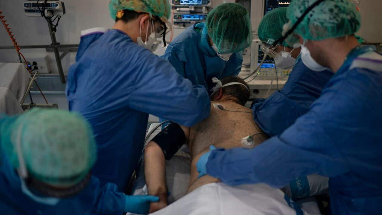 healthcare workers assist a COVID-19 patient at a library that was turned into an intensive care unit (ICU) at Germans Trias i Pujol hospital in Badalona, Barcelona province, Spain. Image credit: AP
