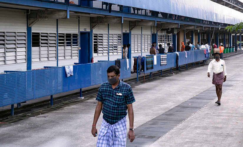 File image of migrant workers wearing protective face masks walk outside their living quarters in Singapore. Ore Huiying © 2020 The New York Times