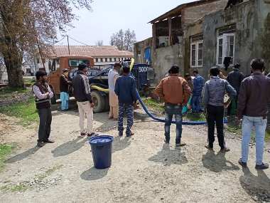 Labourers at a water tank in Baramulla. Image procured by Mudassir Kuloo