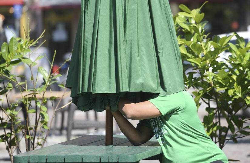An employee of a restaurant at the Paulsplatz square puts up a parasol in Frankfurt, Germany, on 15 May 2020. The restaurants and pubs in Hesse have been allowed to reopen under strict regulations. AP Photo