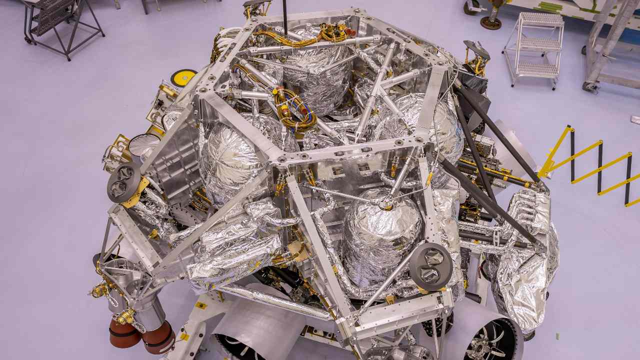 This image of the rocket-powered descent stage sitting on top of NASA's Perseverance rover was taken in a clean room at Kennedy Space Center on April 29, 2020. The integration of the two spacecraft was the first step in stacking the mission's major components into the configuration they will be in while sitting atop of the Atlas V rocket. Image credit: NASA/JPL-Caltech