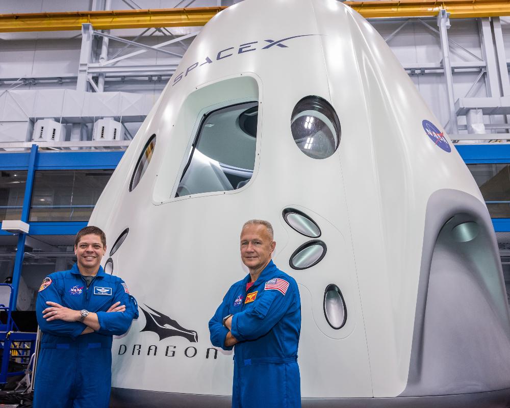 NASA astronauts Bob Behnken and Doug Hurley stand near the cargo dragon. Image credit: NASA 