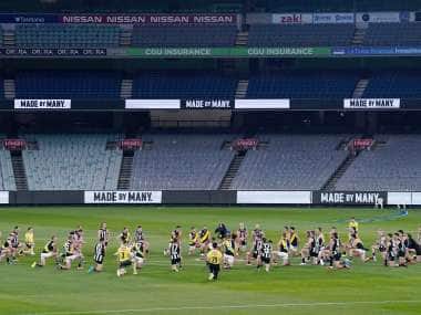 Australian Football League players from rivals Richmond and Collingwood teams, along with game officials, kneel before their game at the Melbourne Cricket Ground in Melbourne, Thursday, June 11, 2020, to show support for the Black Lives Matter movement. Aussie rules football is back after a three-month shutdown due to coronavirus restrictions. (Michael Dodge/AAP Image via AP)