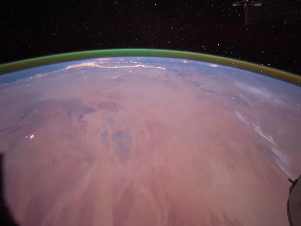 Astronauts aboard the ISS in 2011 saw a green band of oxygen glow is visible over Earth’s curve. On the surface, portions of northern Africa are visible, with evening lights shining along the Nile river and its delta. Image: NASA