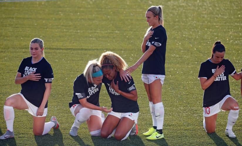 Chicago Red Stars’ Julie Ertz, center left, holds Casey Short, center right, while other players for the Chicago Red Stars kneel during the national anthem before the start of their NWSL Challenge Cup soccer match against the Washington Spirit at Zions Bank Stadium Saturday, June 27, 2020, in Herriman, Utah. (AP Photo/Rick Bowmer)