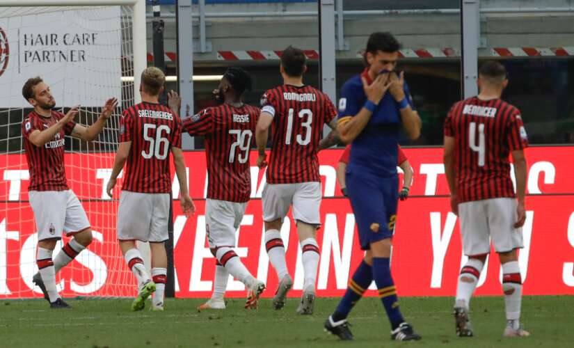 AC Milan's Hakan Calhanoglu, left, celebrates with teammates after scoring his side's second goal during the Serie A soccer match between AC Milan and Roma, at the San Siro Stadium in Milan, Sunday, June 28, 2020. (AP Photo/Luca Bruno)