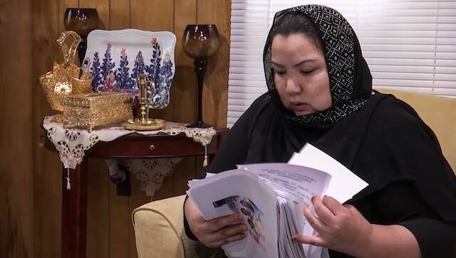 In this image from video, Zumret Dawut, a Uighur woman from China’s far western Xinjiang region, holds documents she brought back from her stay there at her home in Woodbridge, Va., on Monday, June 15, 2020. Dawut says she was forcibly sterilized for having a third child after being released from a Xinjiang detention camp. (AP Photo/Nathan Ellgren)