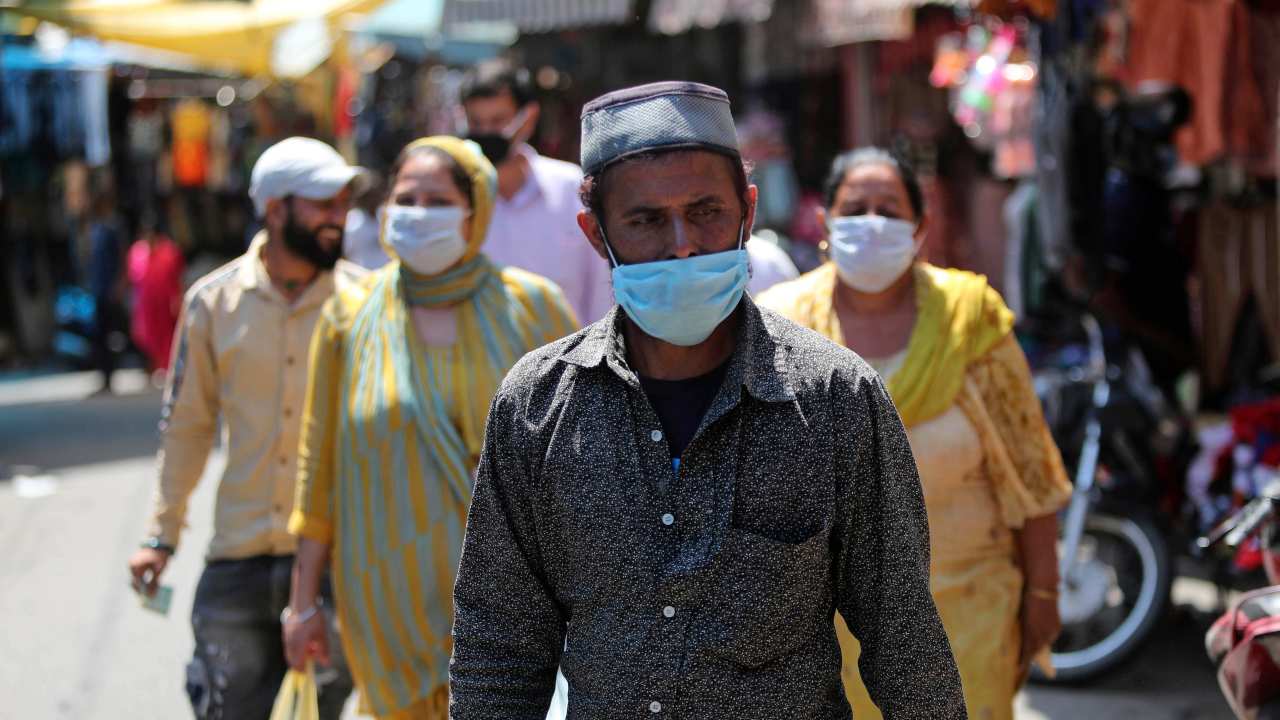 Commuters wearing a mask walk in a Jammu market, as COVID-19 continues to wreak havoc across the board. 