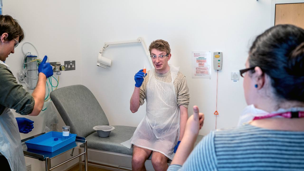 A volunteer receives thumbs up before drinking a solution containing typhoid for a challenge trial at Churchill Hospital in Oxford, England, on Aug. 24, 2017. The idea of human challenge trials for a coronavirus vaccine has provoked fierce debate. (Andrew Testa/The New York Times)