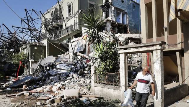 A Lebanese man carries his belongings as he leaves his destroyed house near the scene where an explosion hit on Tuesday the seaport of Beirut, Lebanon. AP
