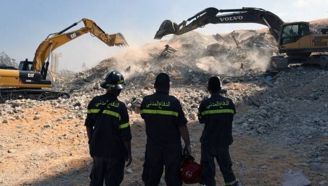 A rescue team watch diggers tackle the removal of debris from this week's massive explosion in the port of Beirut, Lebanon. AP