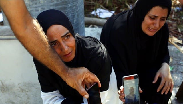 Zeinab Zer Eldin, left, and her sister-in-law shows a photo of her missing husband near the site of the explosion in the port of Beirut, Lebanon. AP