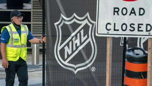 A security guard opens a gate for an empty player bus as it departs the Scotiabank Arena in Toronto, Thursday, Aug. 27, 2020. The NHL has postponed the next two days of playoff games. There has been criticism from Black players who said the league was slow to acknowledge the police shooting of Jacob Blake in Wisconsin. (Frank Gunn/The Canadian Press via AP)