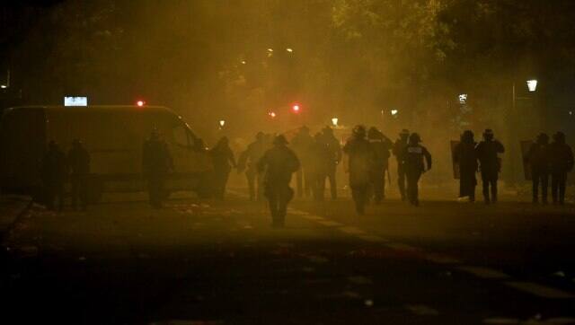 French anti-riot policemen walk in tear gas smokes as they escort PSG supporters around the Parc des Princes stadium. AFP