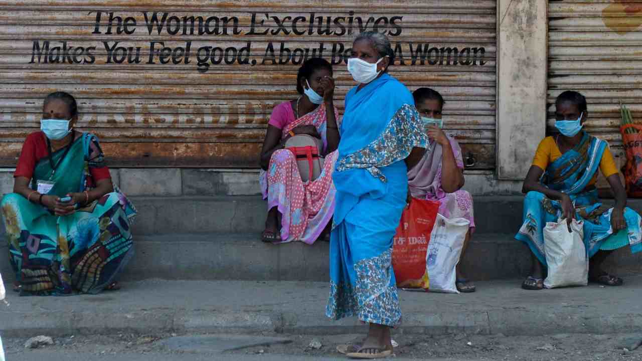 Women wearing facemasks sit in front closed shops during a government-imposed nationwide lockdown. Image: AFP Photo