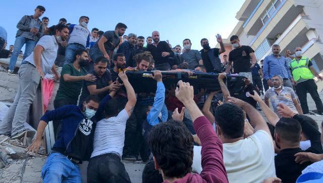Rescue workers and local people carry a wounded person found in the debris of a collapsed building, in Izmir, Turkey. AP