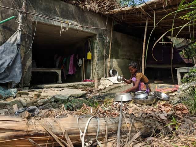 A minor cleans vessels at her makeshift home which is under a bridge on the way to Manik Bishanpur Chand village. Firstpost/Devparna Acharya