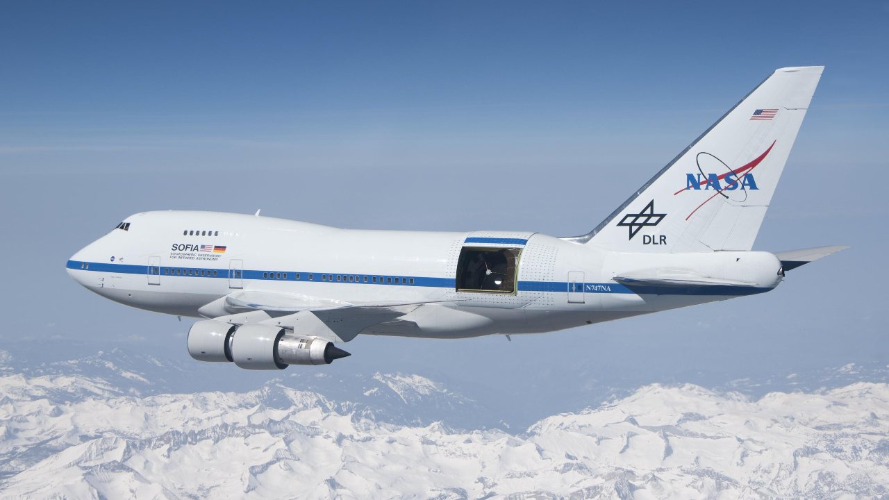 SOFIA soars over the snow-covered Sierra Nevada mountains with its telescope door open during a test flight. SOFIA is a modified Boeing 747SP aircraft. Image Credits: NASA/Jim Ross