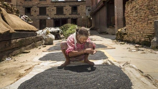 A woman dries lentils in the town square in Bungamati, a village about an hour from Kathmandu. Image via The Third Pole/ Alamy