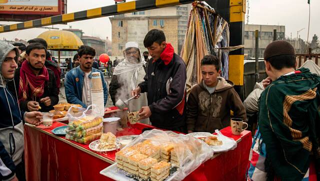 During the morning rush in Kabul, men gather around a street food stall and drink hot milk from communal glasses that are rinsed with water in between uses. By Kiana Hayeri © 2021 The New York Times