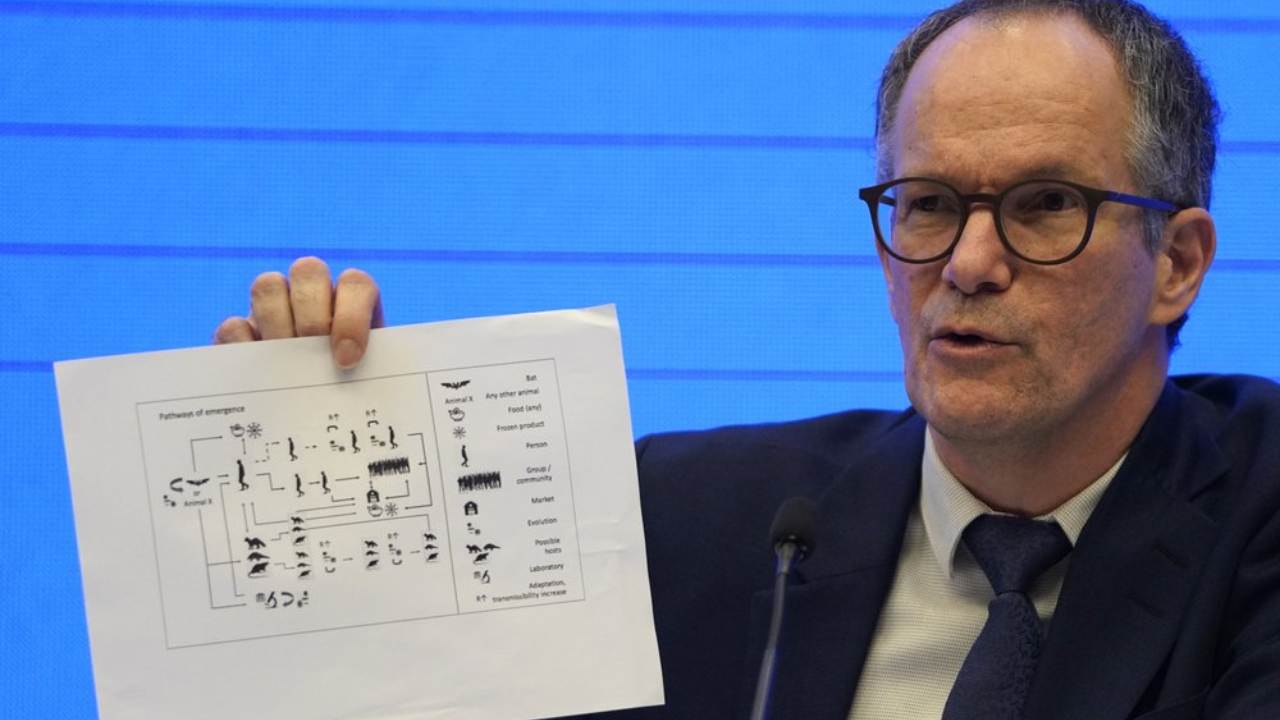 Peter Ben Embarek, of the World Health Organization team holds up a chart showing pathways of transmission of the virus during a joint press conference held at the end of the WHO mission in Wuhan in central China’s Hubei province on Tuesday, 9 February 2021. Image: AP