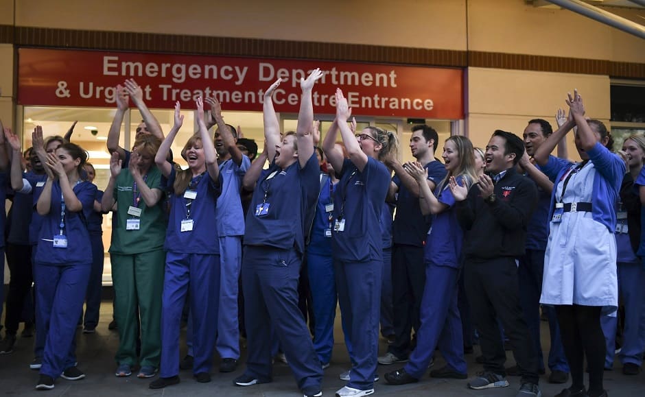 National Health Service (NHS) staff applaud outside the Chelsea and Westminster Hospital in London during the weekly "Clap for our Carers" to show appreciation for health care workers. Photo via AP/Alberto Pezzali
