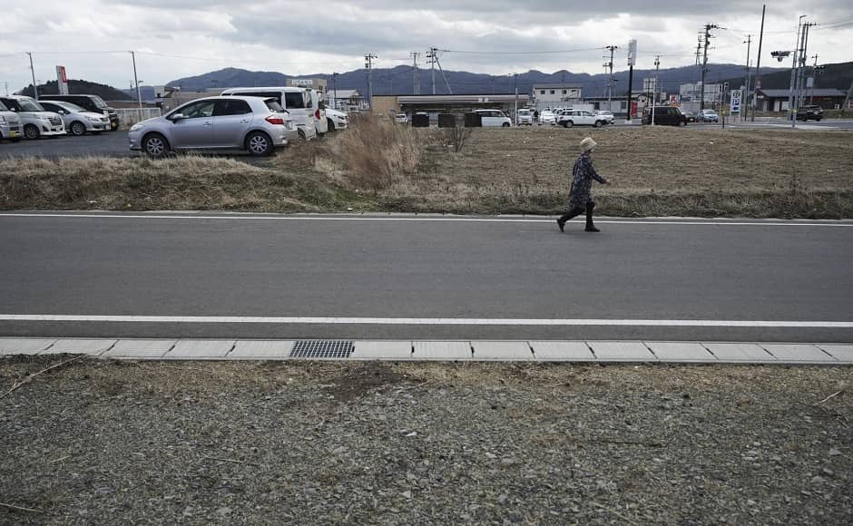 A woman walks through the city nearly ten years after the Tsunami. Image via The Associated Press/Eugene Hoshiko A woman walks through the city nearly ten years after the Tsunami. Image via The Associated Press/Eugene Hoshiko