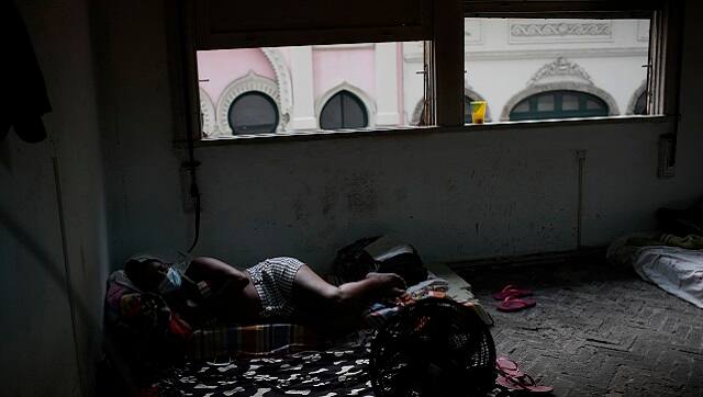 Actress Kelly Regina da Silva lies on a cushion watching TV in the building where she lives in one of the city center’s squats, in Rio de Janeiro, Brazil, in March 2021.