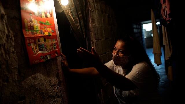 Informal worker Tassiana Nascimento Costa, who made a living hawking bottled water and sodas to tourists before the coronavirus pandemic hit, shows off a poster displaying the frozen treats she now sells to residents, posted inside the occupied building where she lives, in Rio de Janeiro, Brazil. (AP Photo/Silvia Izquierdo)