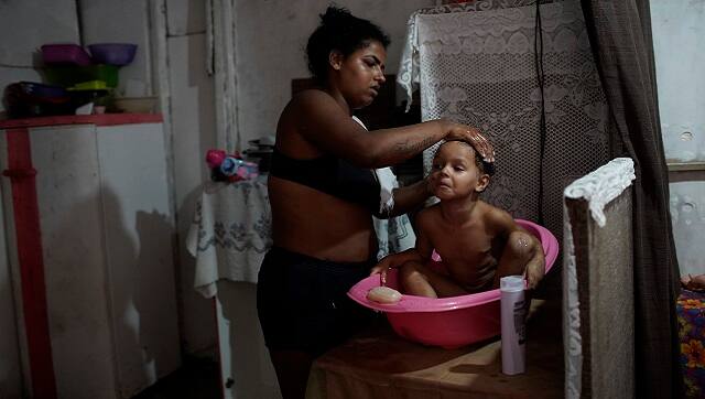 Thayane, who made a living as a manicurist before the coronavirus pandemic hit, bathes her 3-year-old daughter Melyssa in their room of an occupied building where she lives with her three daughters in Rio de Janeiro. (AP Photo/Silvia Izquierdo)