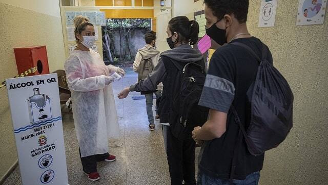 Marilene Paixao, the mother of a student, checks the temperature of students entering the EMEF Sylvia Martin Pires public school in Sao Paulo. (AP Photo/Andre Penner, File)