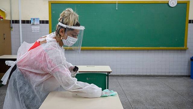 Marilene Paixao, the mother of a student, disinfects a desk in a classroom of the EMEF Sylvia Martin Pires public school in Sao Paulo. (AP Photo/Andre Penner, File)