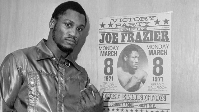 FILE - Heavyweight champ Joe Frazier poses by a poster advertising his 