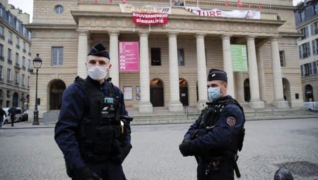 Police officers stationed outside the Odeon theatre as French culture and tourism workers protest against unemployment within. Image via The Associated Press/ Francois Mori