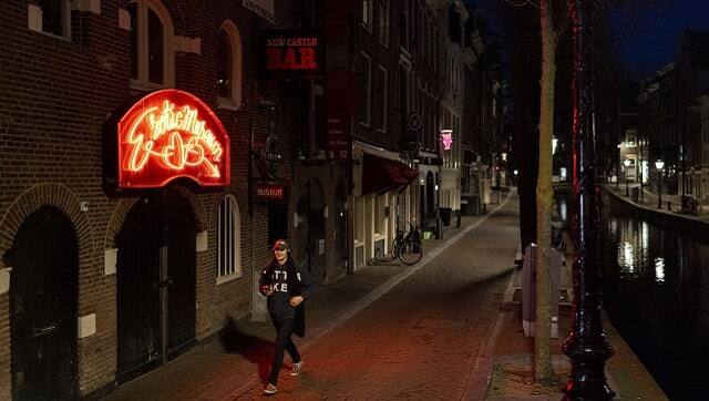 A man walks through the nearly-deserted Red Light District of Amsterdam in March 2021. (Ilvy Njiokiktjien/The New York Times)