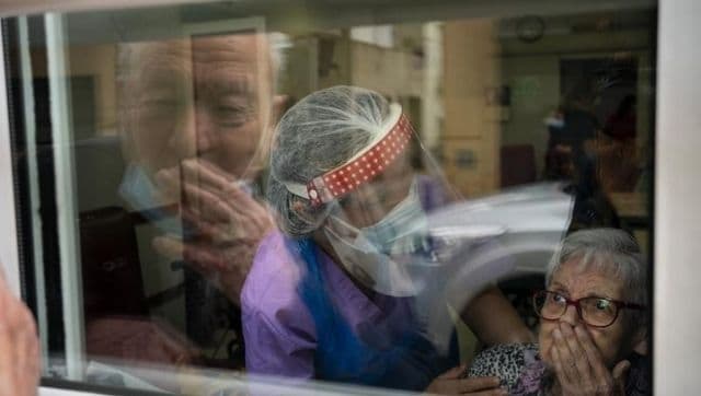 In Spain, an elderly couple separated after the pandemic overcome grief through a glass pane