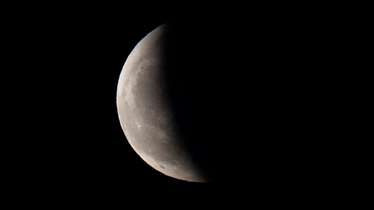 बीजिंग के ऊपर आसमान में चंद्र ग्रहण के दौरान एक बादल के पीछे से निकलते ही पृथ्वी की छाया आंशिक रूप से चंद्रमा को ढक लेती है।  चीन।  छवि क्रेडिट: एपी फोटो/एनजी हान गुआन)